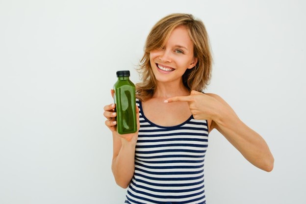 A woman holding a greens drink.