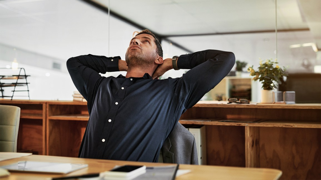 A man sitting at a desk taking a stretch break.