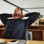 A man sitting at a desk taking a stretch break.