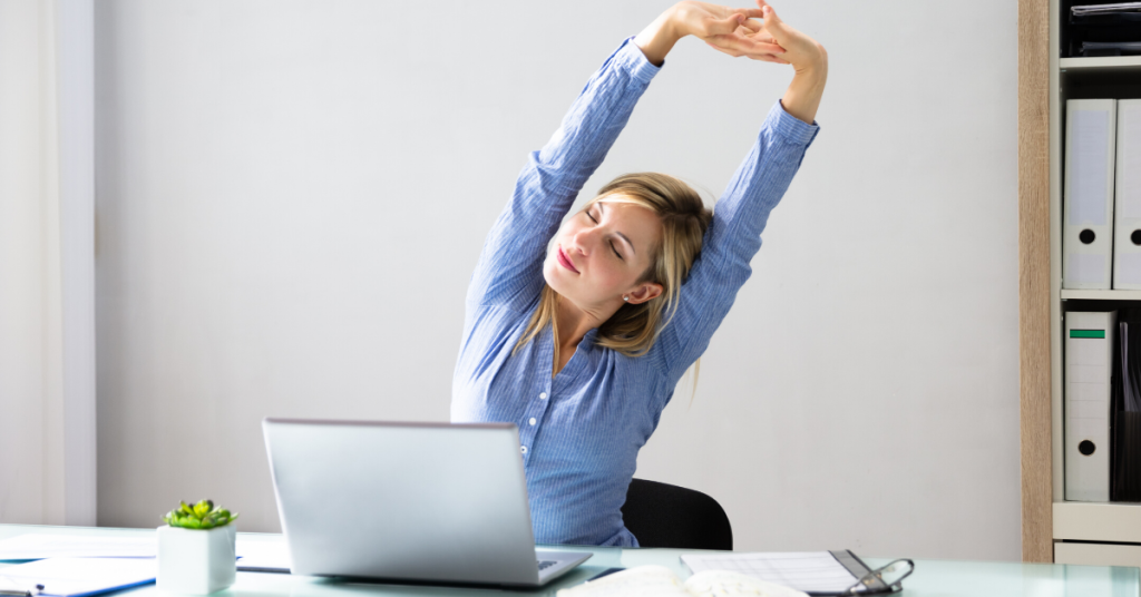 A woman stretching at her desk