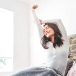 a woman in bed waking up and stretching