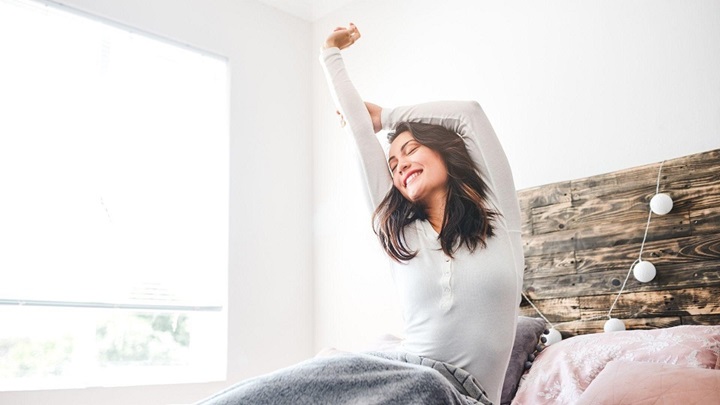 a woman in bed waking up and stretching