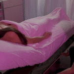 a woman lying on a massage table with a heated blanket and a massage therapist
