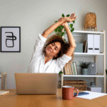 A woman stretching at her desk.