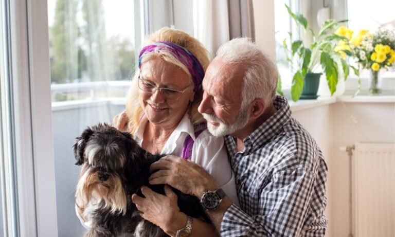 An image of 2 seniors holding a dog.