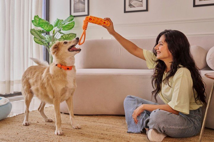 A woman sitting on the floor playing with her dog.