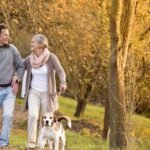 A man and woman walking with their dog.