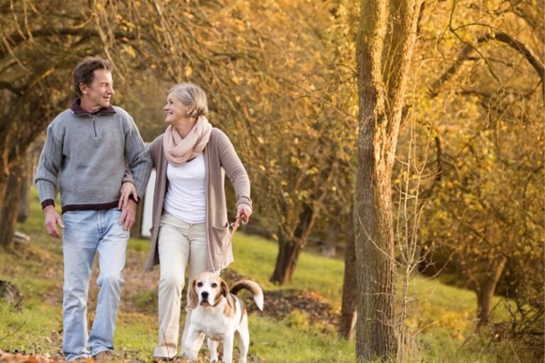 A man and woman walking with their dog.
