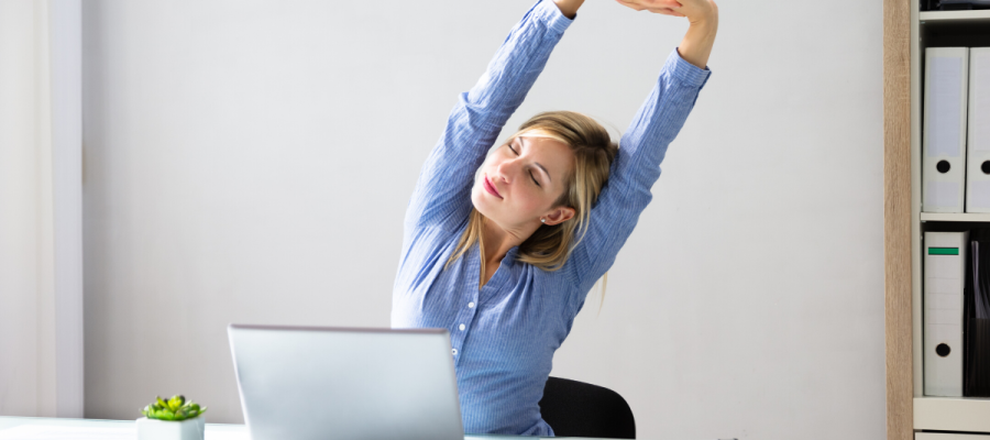 A woman stretching at her desk