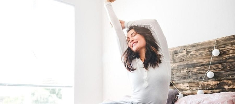 a woman in bed waking up and stretching