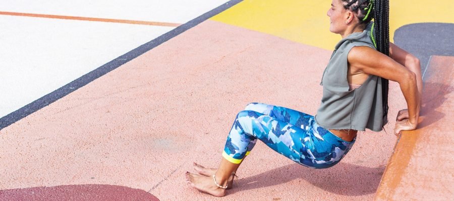 A woman doing dips in a park.