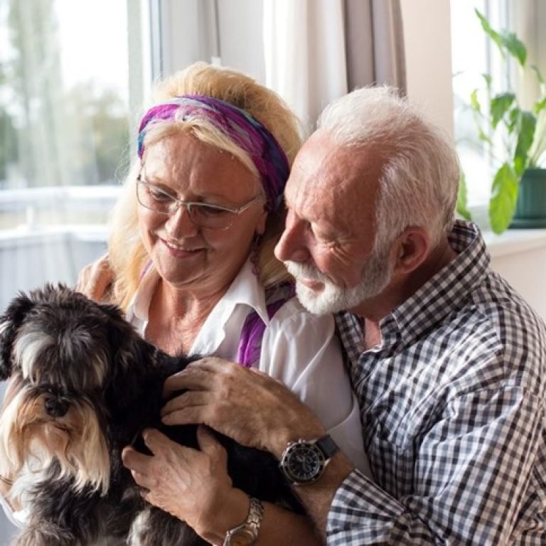 An image of 2 seniors holding a dog.